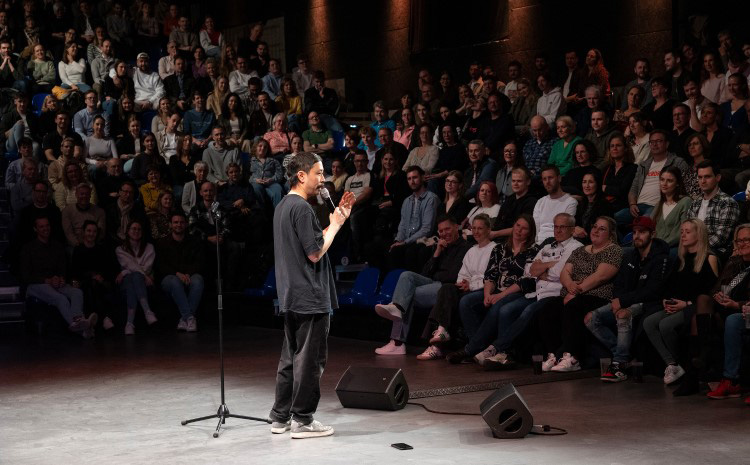 Ein Stand-Up-Comedian am Mikrophon in der Quatsch Comedy Live Show vor vielen Zuschauern.