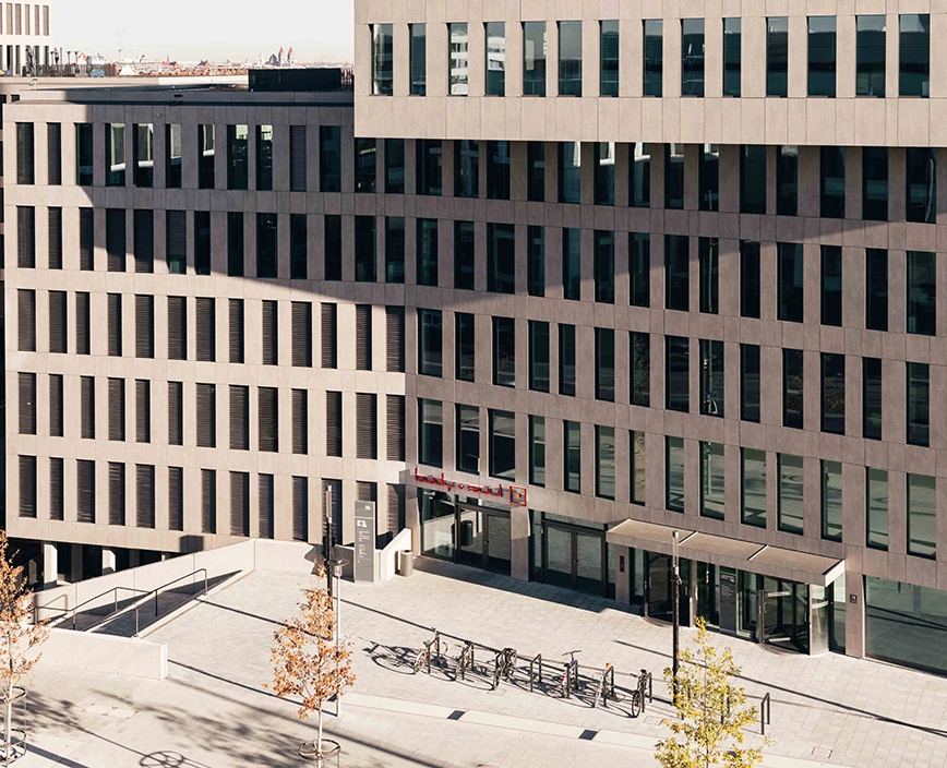 Center Hirschgarten – Gebäudeansicht mit Eingangsbereich aus erhöhter Perspektive, mit einigen geparkten Fahrrädern vor dem Center.