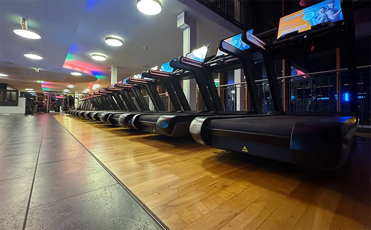 Mehrere Laufbänder in einem großzügigen, leeren Fitnessstudio.