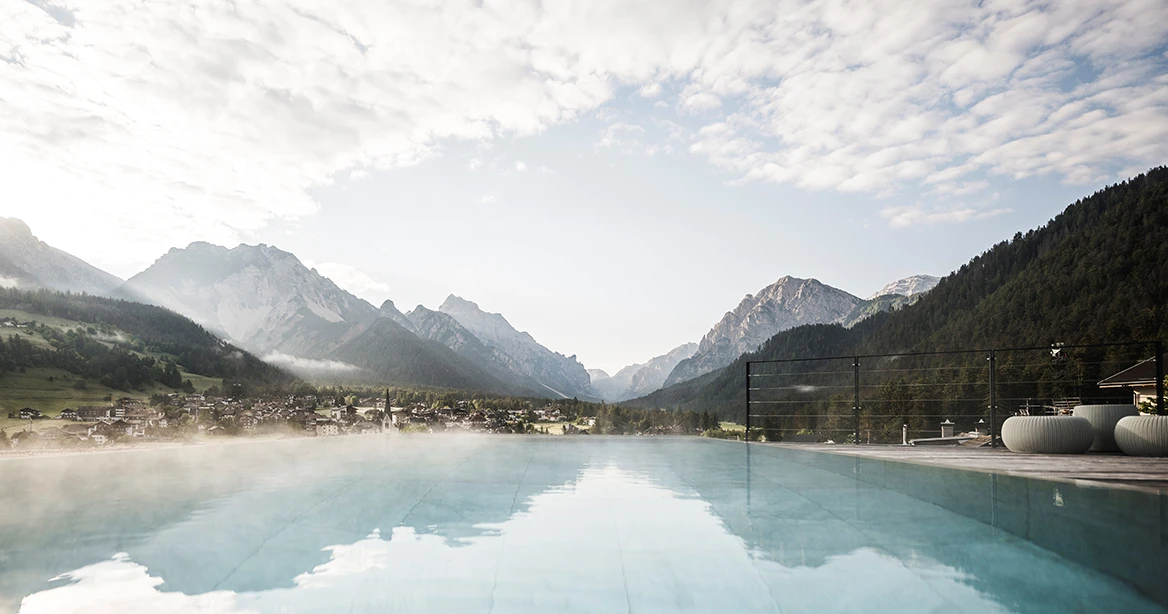 Ein dampfender Hotelaußenpool inmitten einer Berglandschaft in Südtirol.