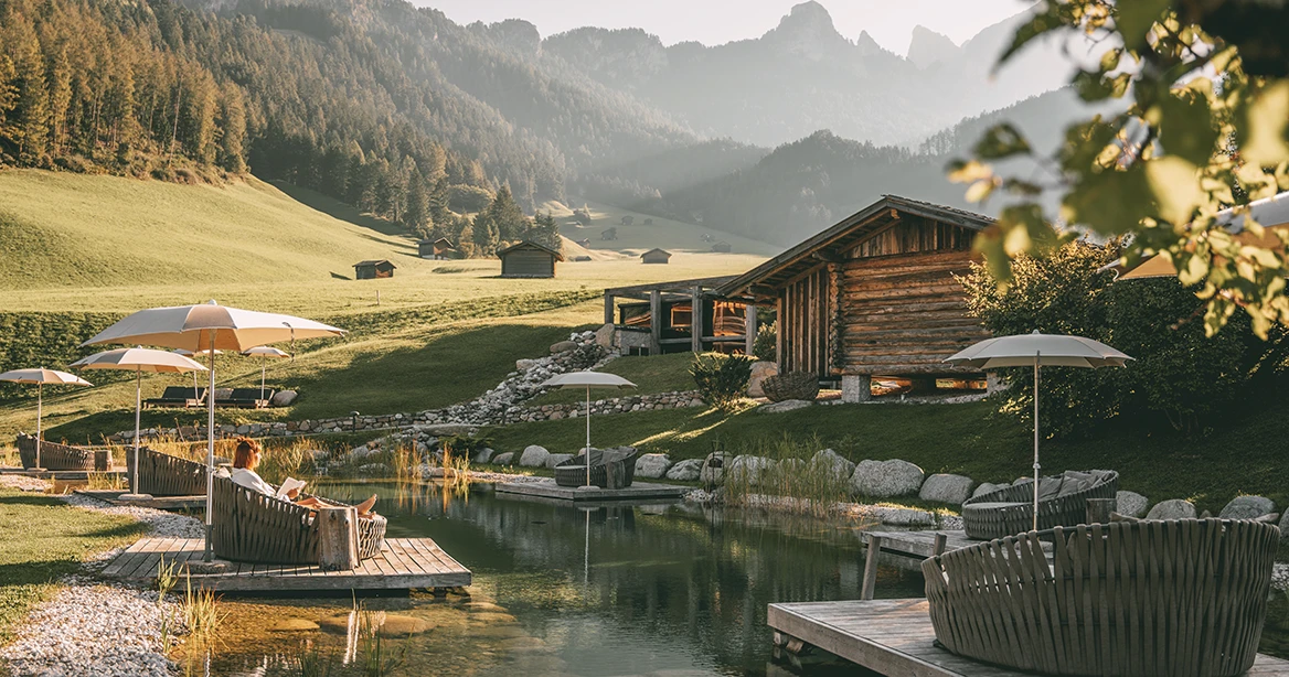 Natürlicher Badeteich im Herbst, mit Blick auf die Bergkulisse in den Dolomiten.