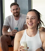 Ein Mann und eine Frau sitzen im Fitnessstudio und trinken gemeinsam Shakes.