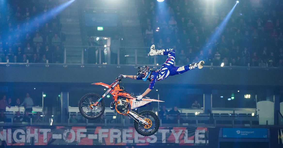 Ein Motorradfahrer wirbelt an seinem Motorrad durch die Luft bei einer Stunt-Show in der Münchner Olympiahalle.