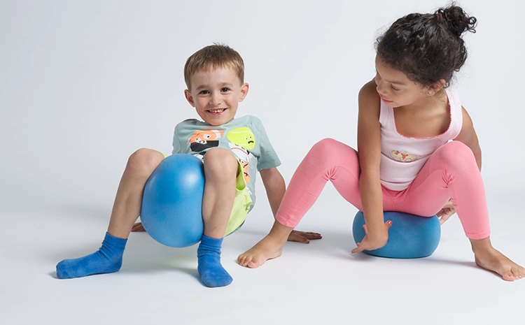 2 Kinder mit Bällen auf dem Boden.
