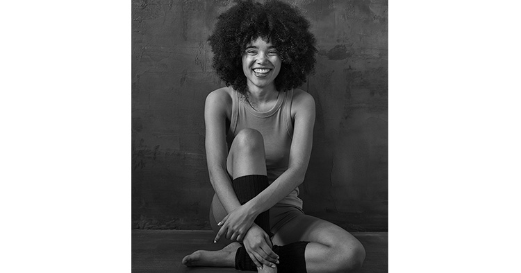 Sitzende Frau lacht in die Kamera im Fotostudio von Deidl und Behnke.