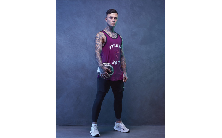 Junger Mann im Basketball-Outfit posiert mit Basketball im Fotostudio von Deidl und Behnke.